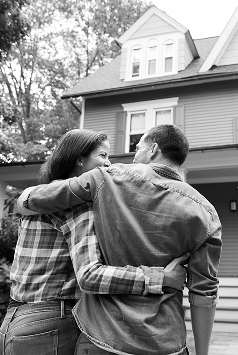 Couple hugging in front of home