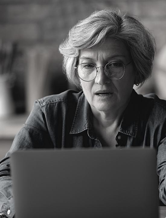 older woman with glasses in front of laptop