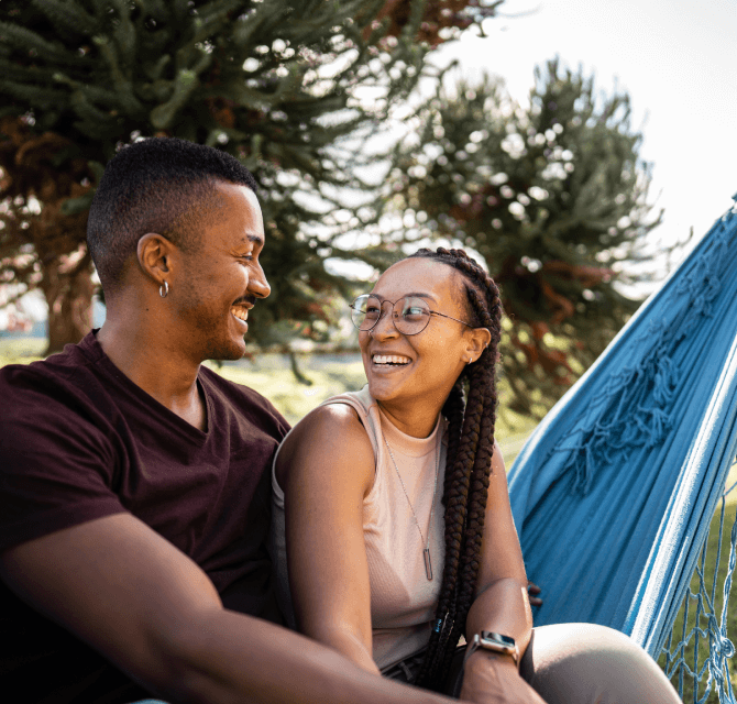 couple smiling while sitting on hammock