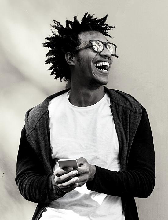 man smiling to the right holding phone wearing sunglasses