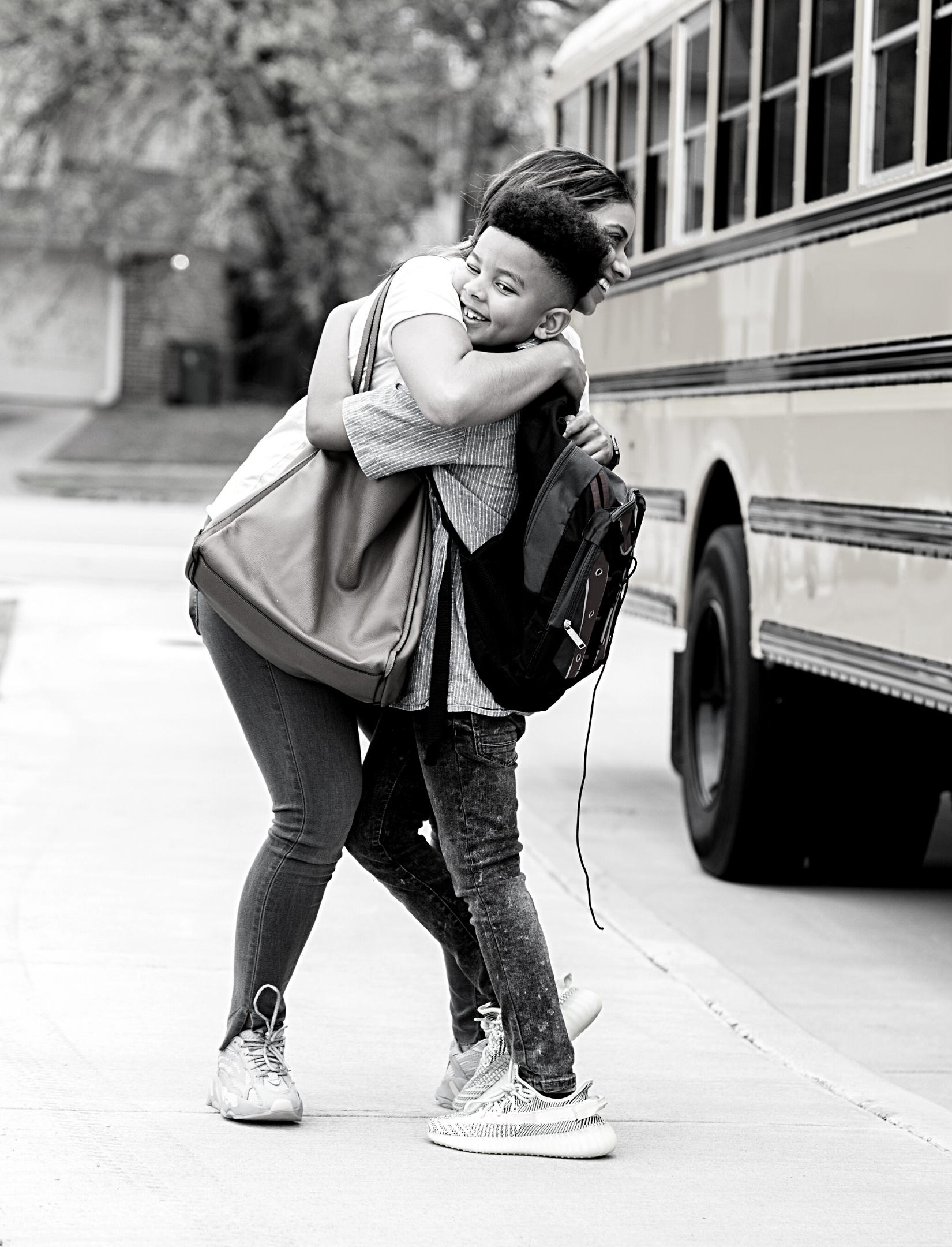 mom hugging son at bus stop