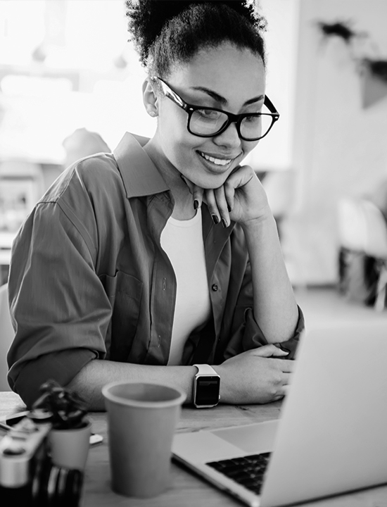 Girl with glasses looking at laptop with coffee