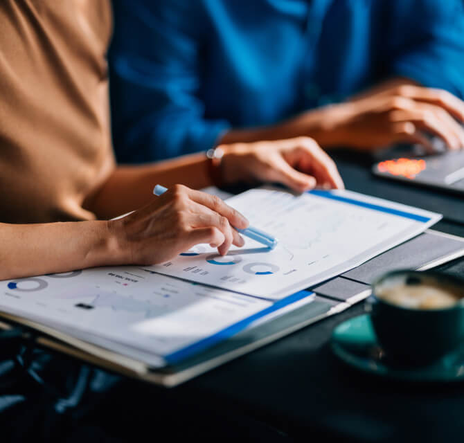 2 people in a meeting looking at binder of charts